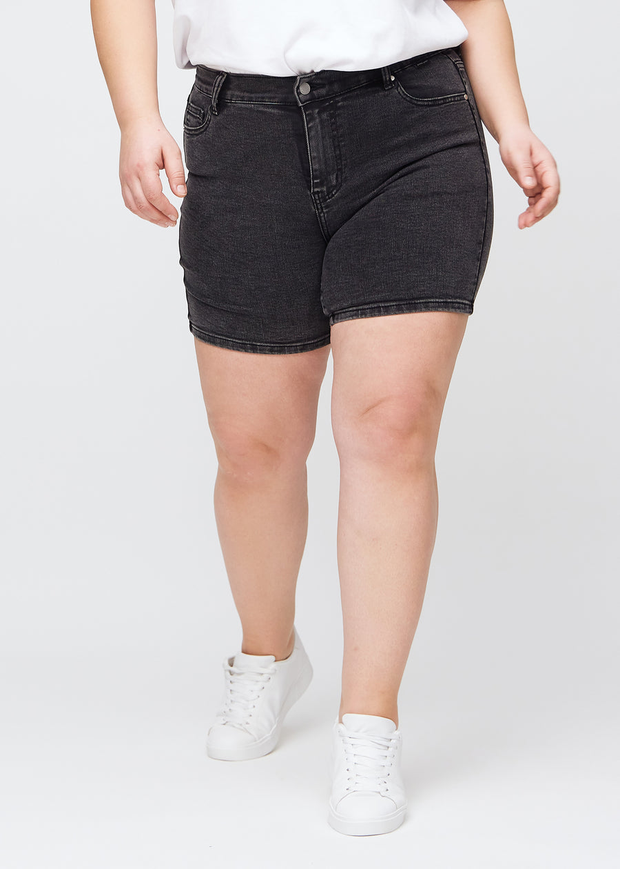 Dunkelgraue Denim-skinny-Short Shorts, Modellname Shadows, die eng anliegen und bei einem Plus-Size-Model bis zur Mitte des Oberschenkels reichen, von vorne gesehen.