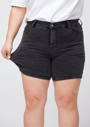 Das Plus-Size-Model zieht die Shorts am Oberschenkel, um den Stretch zu zeigen.