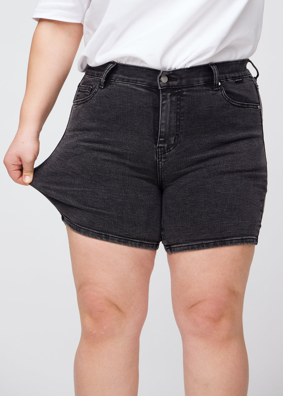 Das Plus-Size-Model zieht die Shorts am Oberschenkel, um den Stretch zu zeigen.