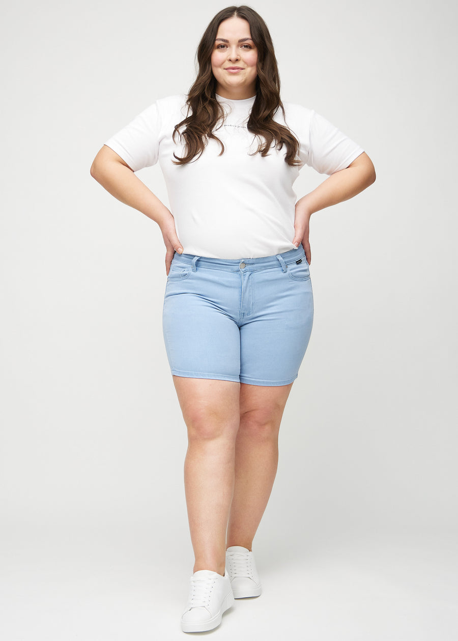 Ganzkörperbild eines Plus-Size-Models in hellblauen skinny short shorts.