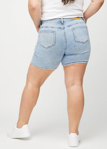 Hellblaue Denim-skinny Short Shorts von hinten an einem Plus-Size-Model gesehen, sodass man das gesamte Produkt sehen kann.