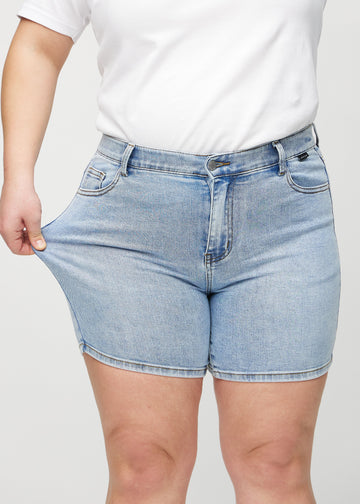 Das Plus-Size-Model zieht die Shorts am Oberschenkel, um den Stretch zu zeigen.