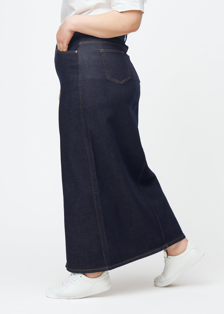 Langer tief dunkelblauer Denim-Rock für Damen in der Farbe Midnights, von der Seite auf einem Plus-Size-Model gesehen, mit sichtbarem Schlitz vorne.