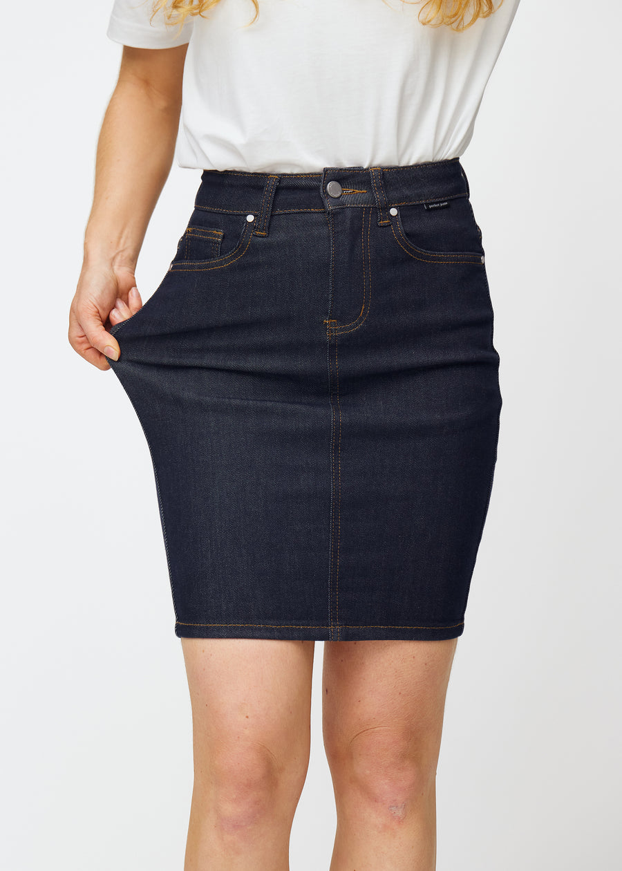 Model dehnt tief dunkelblaue Denim-Rock für Damen in der Farbe Midnights am Oberschenkel, um den Stretch des Materials zu zeigen.
