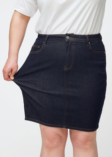 Plus-Size-Model dehnt tief dunkelblaue Denim-Rock für Damen in der Farbe Midnights am Oberschenkel, um den Stretch zu zeigen.