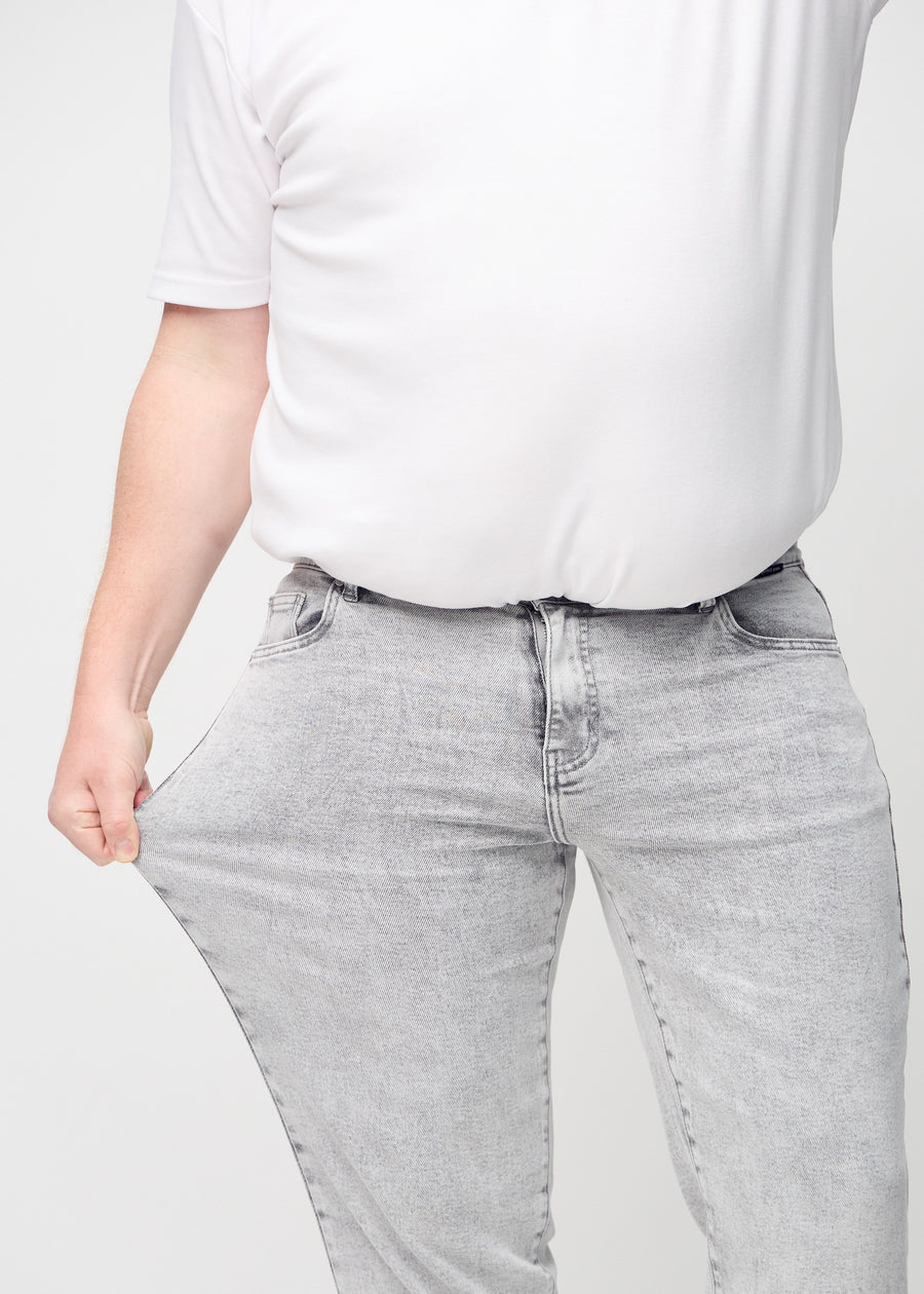 Das Plus-Size-Model zieht die Jeans am Oberschenkel auseinander, um den Stretch zu zeigen.