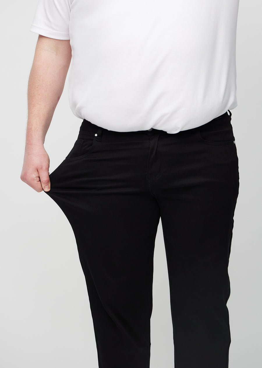 Das Plus-Size-Model zieht die Jeans am Oberschenkel auseinander, um den Stretch zu zeigen.