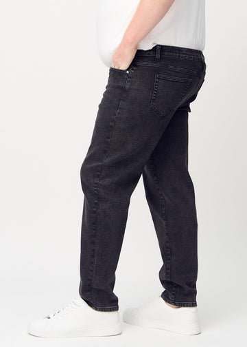 Dunkelgrauer Denim regular jeans von der Seite an einem Plus-Size-Model gezeigt.