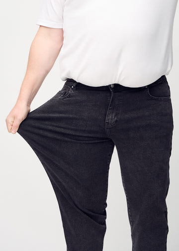 Das Plus-Size-Model zieht die Jeans am Oberschenkel auseinander, um den Stretch zu zeigen.