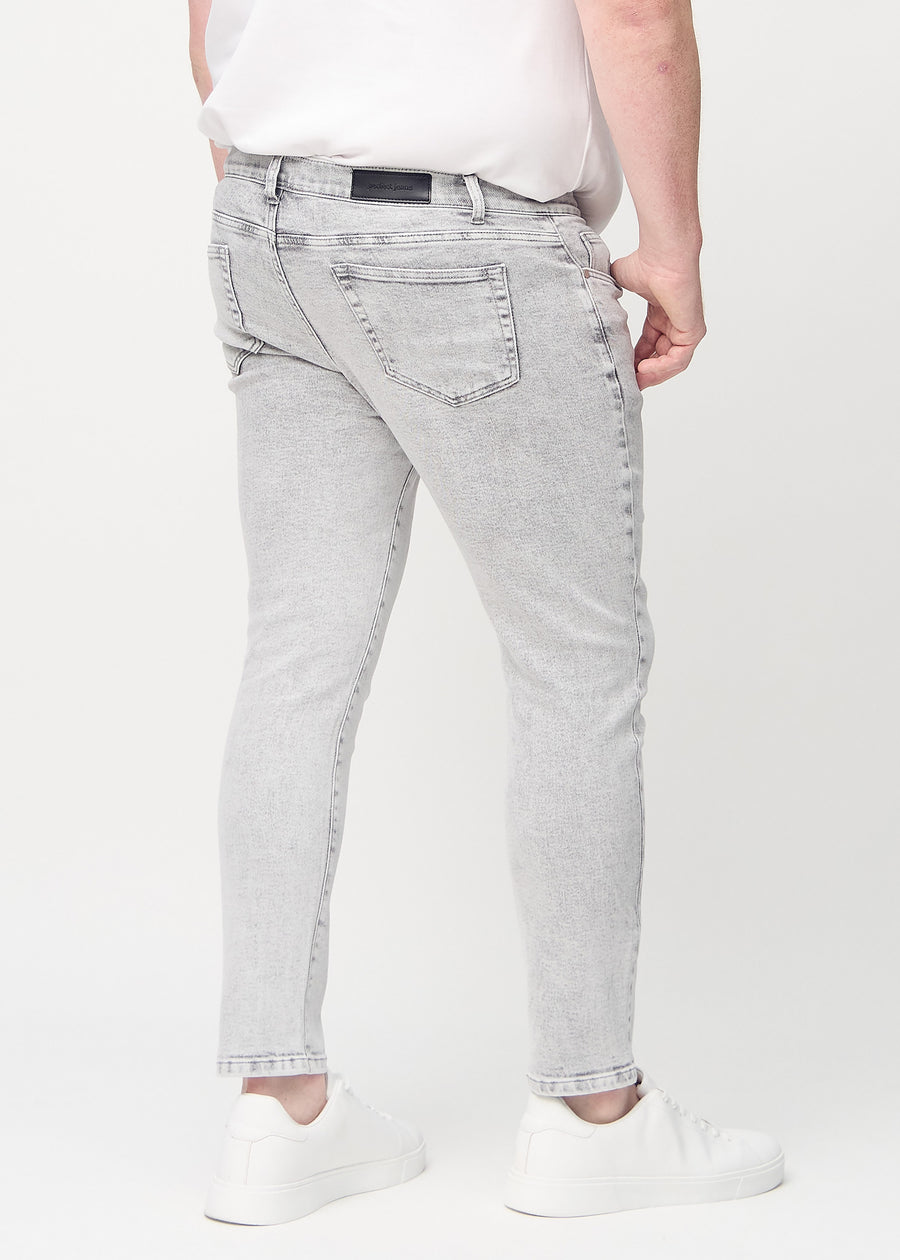 Hellgraue Denim-Jeans im Slim Fit, von hinten an einem Plus-Size-Model gesehen, um die gesamte Jeans zu zeigen.