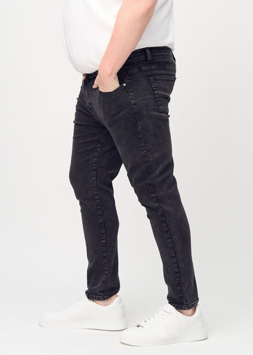 Dunkelgraue Denim-Jeans im Slim Fit, von der Seite an einem Plus-Size-Model gesehen.