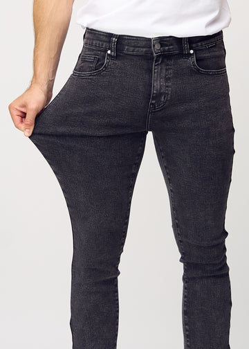 Ein Model dehnt die Jeans am Oberschenkel, um den Stretch des Materials zu zeigen.