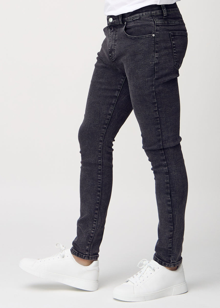 Dunkelgraue Denim-Jeans im Slim Fit, von der Seite an einem Model gesehen.