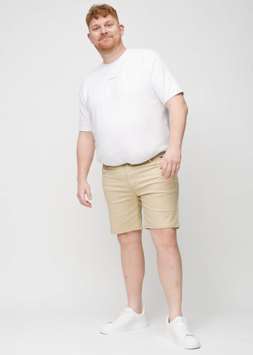 Ganzkörperbild eines Plus-Size-Models in beige middle-slim Shorts.