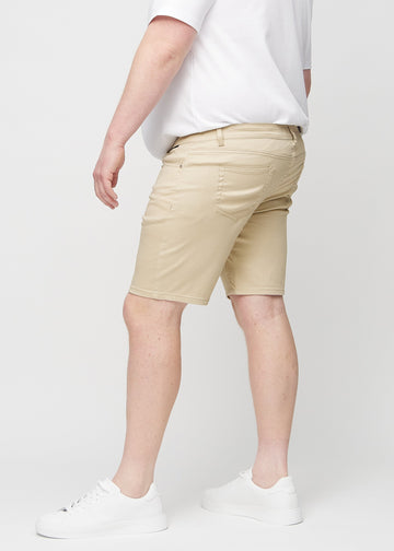 Beige middle-slim Shorts an einem Plus-Size-Model von der Seite gesehen.
