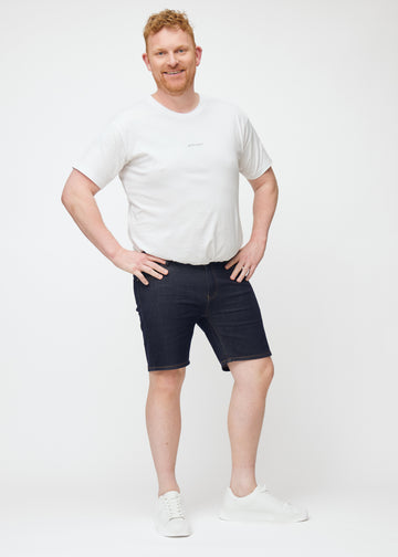 Ganzkörperbild eines Plus-Size-Models in tief dunkelblauen Denim-Shorts für Herren in der Farbe Midnights mit Slim-Passform.