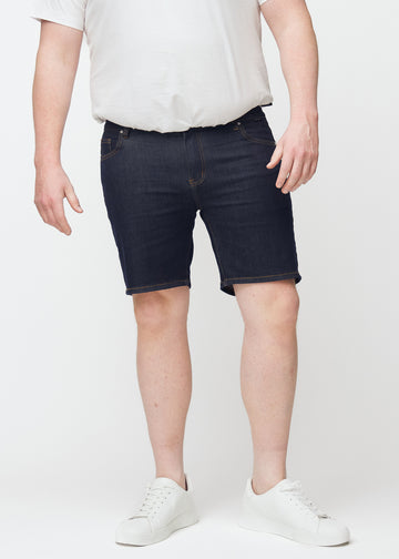 Tief dunkelblaue Denim-Shorts für Herren in der Farbe Midnights mit Slim-Passform, von vorne auf einem Plus-Size-Model gesehen.