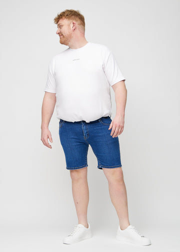 Ganzkörperbild eines Plus-Size-Models in dunklen Denim-Middle-slim-Shorts.