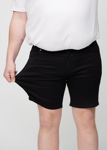 Das Plus-Size-Model zieht die Shorts am Oberschenkel auseinander, um den Stretch zu zeigen.