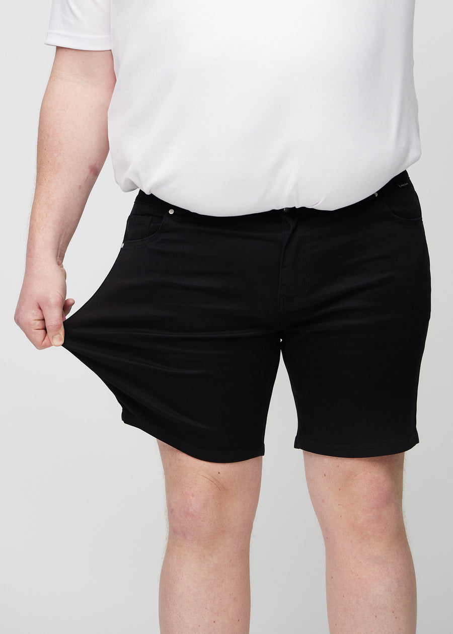Das Plus-Size-Model zieht die Shorts am Oberschenkel auseinander, um den Stretch zu zeigen.