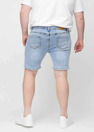 Hellblaue Denim middle-slim Shorts von hinten an einem Plus-Size-Model gesehen, sodass man das gesamte Produkt sehen kann.