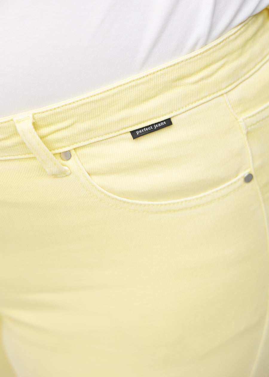 Forlommen på et par lysegule skinny short shorts, hvor man kan se logoet på en plus-size model.